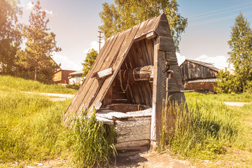 Obraz premium Old abandoned wooden well with beautiful structure in the Siberian village. Sunset