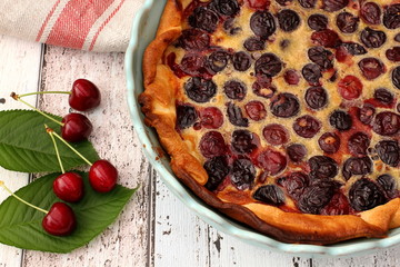 Homemade Cherry tart with raw cherries and linen kitchen towel on wooden table