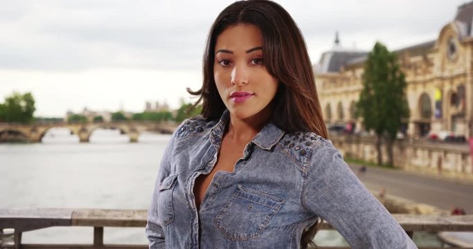 Portrait of pretty Latina female on a bridge in Paris, Confident young woman smiling directly at camera, 4k