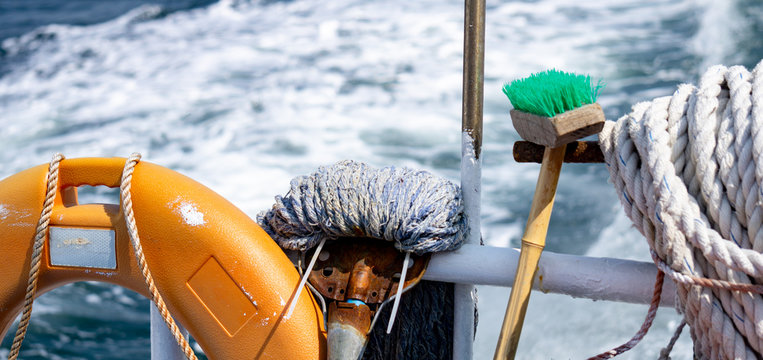 Cleanliness tool including mob and brush with handle, Safety buoy and old white rope at the stern of island ferry near coastalline in Geoje island, South Korea