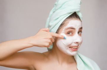 Happy woman with towel on her head make a facial mask. Skin care treatment concept.