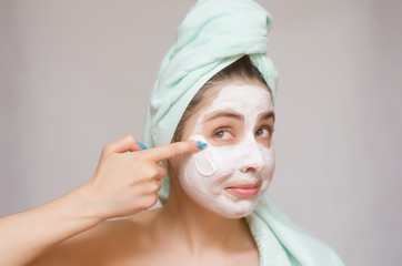 Happy woman with towel on her head make a facial mask. Skin care treatment concept.