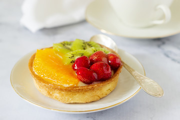 Mini cake or tart with custard and various fruits in jelly.