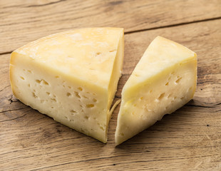 Pieces of homemade cheese on the wooden background.