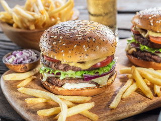 Hamburgers and French fries on the wooden tray.