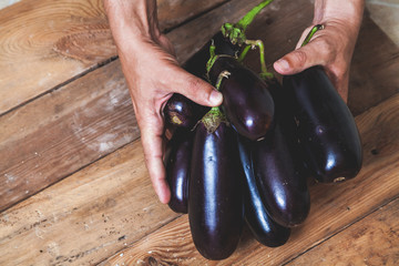 Hands take few eggplants on wooden boards