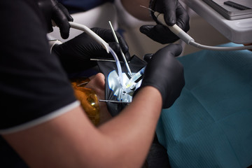 Close-up process of male professional dentist surgeon performing operation install dental implant teeth of man patient in clinic. Black gloves and shape, modern installations