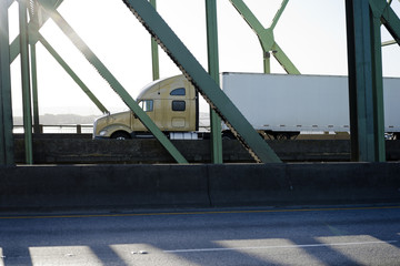 Big rig semi truck with semi trailer driving on bridge in sunshine