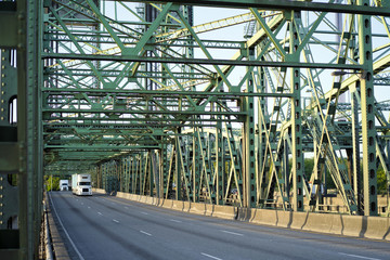 Big rigs semi trucks convoy driving on Columbia Interstate lift bridge with arched metal trusses