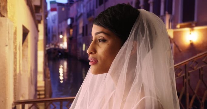 Side view of blushing bride in Venice, Italy joyful and excited, Black woman in traditional veil looking off camera, smiling and happy, 4k