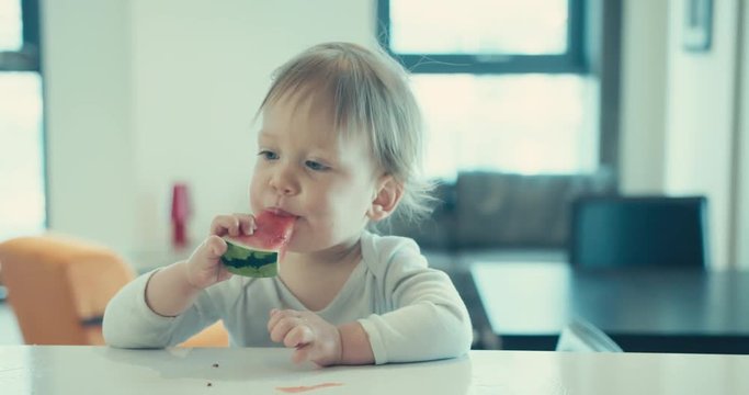 Little boy eating watermelon at home in apartment