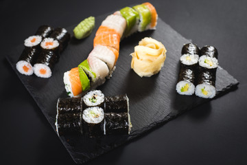 A set of different sushi rolls with caviar on black background