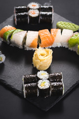 A set of different sushi rolls with caviar on black background