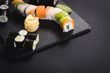 A set of different sushi rolls with caviar on black background