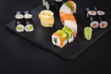 A set of different sushi rolls with caviar on black background