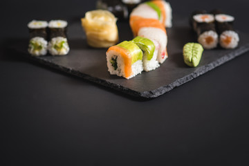 A set of different sushi rolls with caviar on black background