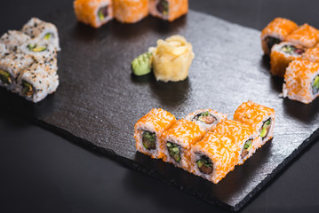 A set of different sushi rolls with caviar on black background
