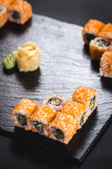 A set of different sushi rolls with caviar on black background