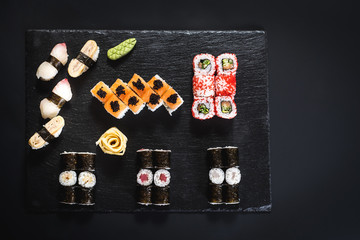 A set of different sushi rolls with caviar on black background