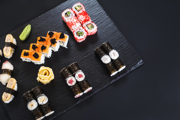 Fototapeta na wymiar A set of different sushi rolls with caviar on black background