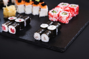 A set of different sushi rolls with caviar on black background