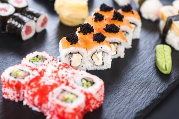 A set of different sushi rolls with caviar on black background
