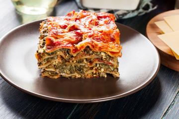 Piece of tasty hot lasagna with spinach on a plate