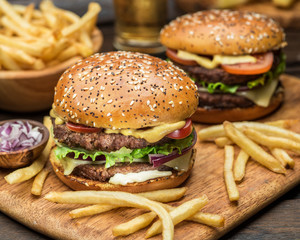 Hamburgers and French fries on the wooden tray.