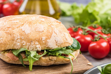 Fresh bun with rocket salad on wooden board