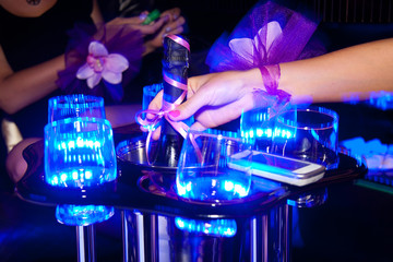 close up female hand reaches for a bottle of champagne at night party. hen-party before the wedding
