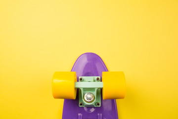 purple youth skateboard on yellow background. children's plastic mini cruiser board. minimalism, flat lay, copy space