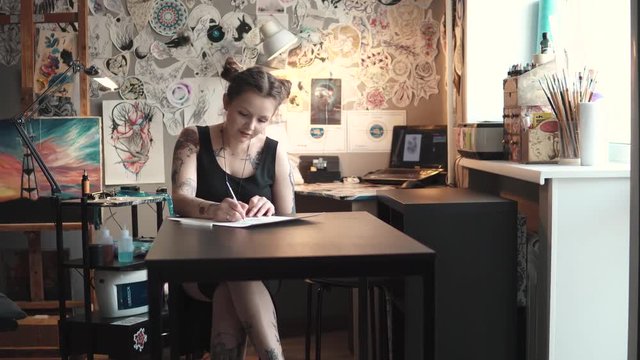 tattoo artist makes a sketch of tattoo on paper in a home Studio