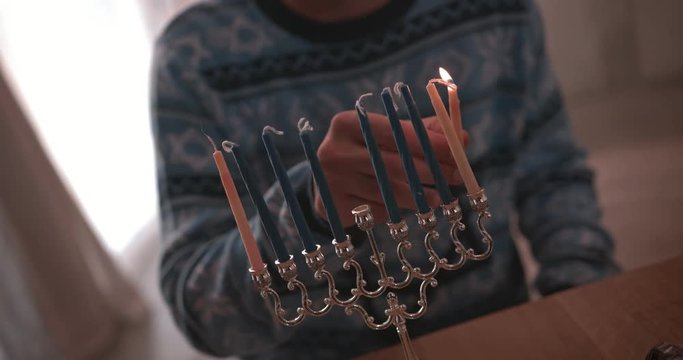 Man lighting candles on menorah celebrating Hanukah