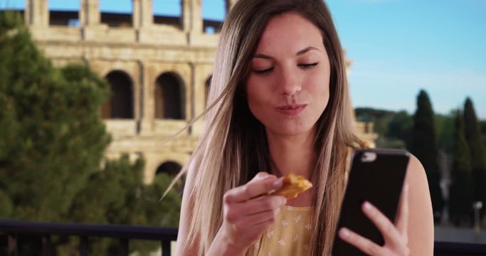 Close-up of girl taking selfie with phone while eating pizza by Coliseum in Rome, Pretty woman taking selfie photo and eating slice of authentic pizza while in Rome, 4k