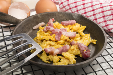 scrambled eggs in a cast iron pan with fried bacon bits