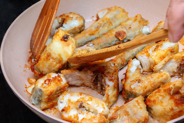 Pieces of fish fried in a hot pan