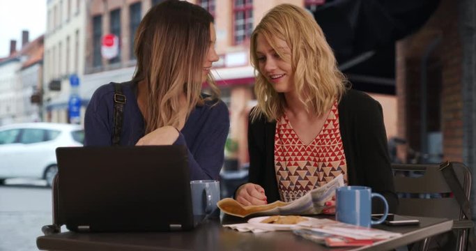 Two lost girls using smartphone and laptop to locate destination in Bruges, Belgium, Two cute young adult women looking at cell phone with map in European city, 4k
