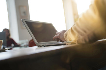 Closeup of man with laptop writing on paper