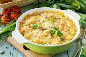 Casserole crumble with red fish, white bread and cheese on the kitchen wooden table. Proper nutrition.