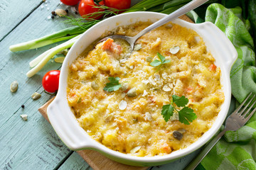 Casserole crumble with red fish, white bread and cheese on the kitchen wooden table. Proper nutrition.