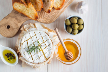 Camembert and brie cheese on wooden background with tomatoes, letuce and garlic. Italian food. Dairy products.