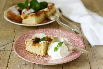 Pie with plums and peaches, served with a vanilla ice cream ball and lemon balm leaves.