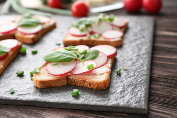 Toasted bread with radish on slate plate, closeup