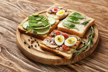 Different delicious toasts on wooden board