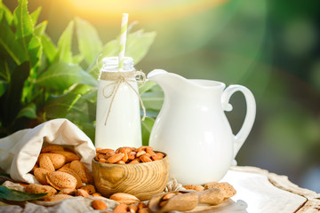 Almond and almond milk on a wooden table in the summer garden. Useful food.