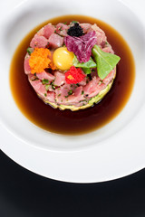 Tasty tartar salad on black background