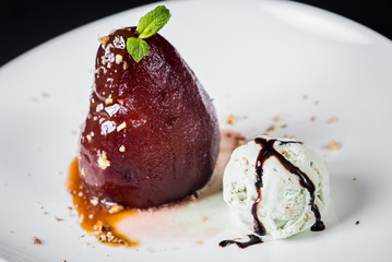 A dessert with caramelized pear and ice on black background