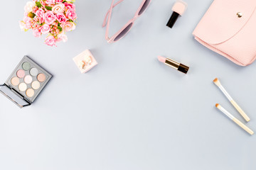 Fashion blogger workspace flat lay with cosmetics, purse, planner book and flowers.