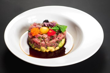 Tasty tartar salad on black background