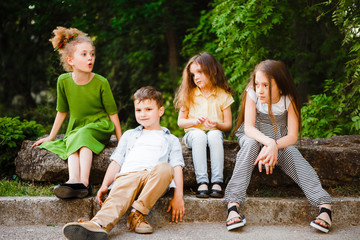 A group of children of school and preschool age are sitting in the park.